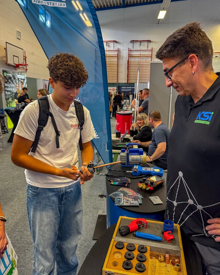 A teenager is holding a pipe cutter; next to him is a member of staff from KSI Kältetechnik
