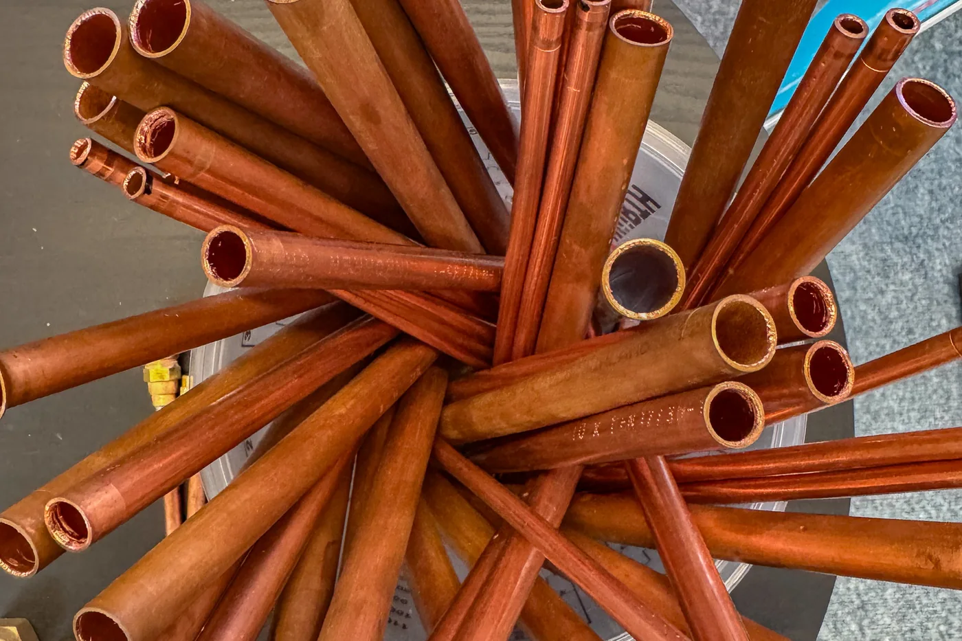 Cut-to-size copper pipes are arranged in a star shape inside a container on the exhibition table at KSI Kältetechnik